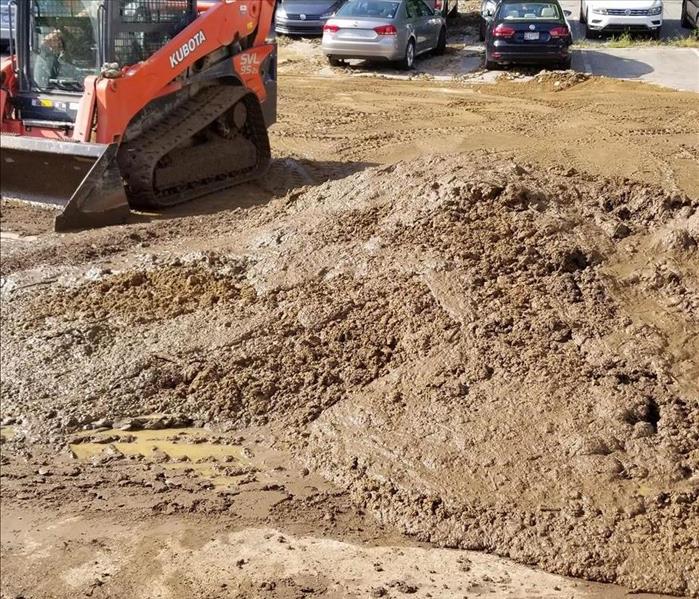 heavy equipment cleaning up mud in parking lot