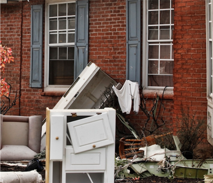 < img src =”damage.jpg” alt = "damaged furniture and other home items sitting outside of red brick house ” >