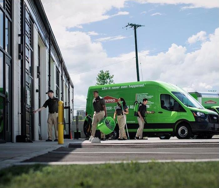 < img src =”crew.jpg” alt = "a group of employees with restoration tools walking away from SERVPRO van" >